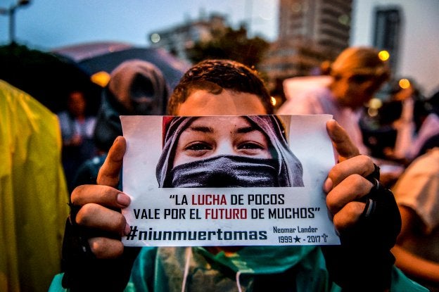Un joven muestra un cartel con el rostro de una de las víctimas durante las protestas. :: f. parra / afp