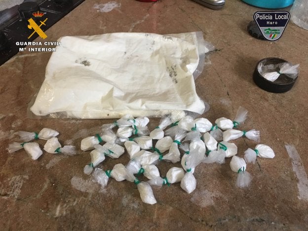 El detenido escoltado por un agente, plantas de marihuana y droga intervenida en el domicilio de Haro. :: guardia civil