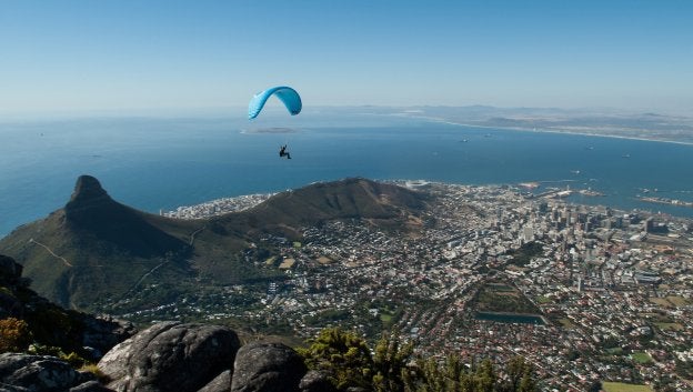 Un joven en parapente sobrevuela Ciudad del Cabo, una de las bahías más bellas del mundo. La Montaña Mesa envuelve un asentamiento que se remonta al siglo XVII. ::