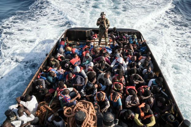 Un guardia costero sube a una embarcación que trasladaba a 150 inmigrantes desde Libia. :: afp/