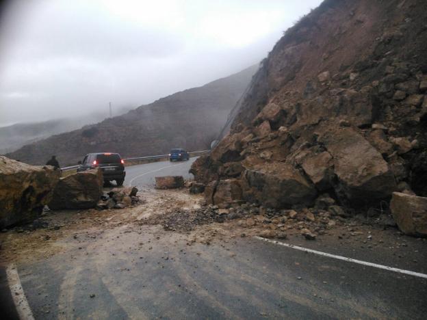 Un coche sortea enormes rocas caídas a la carretera tras un desprendimiento en la LR-250, en Soto en Cameros. :: B.A./
