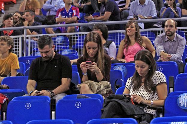 Varias personas usan su
teléfono móvil en un partido
de baloncesto. :: j. andrade/