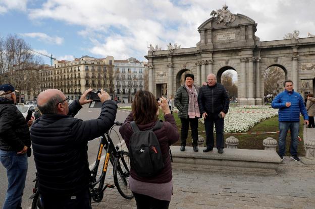 Varios turistas se fotografían ante la Puerta de Alcalá, en Madrid. :: Chema Moya / Efe/