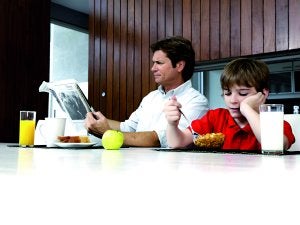 En familia. Un padre lee el periódico mientras su hijo desayuna. ::
EFE/